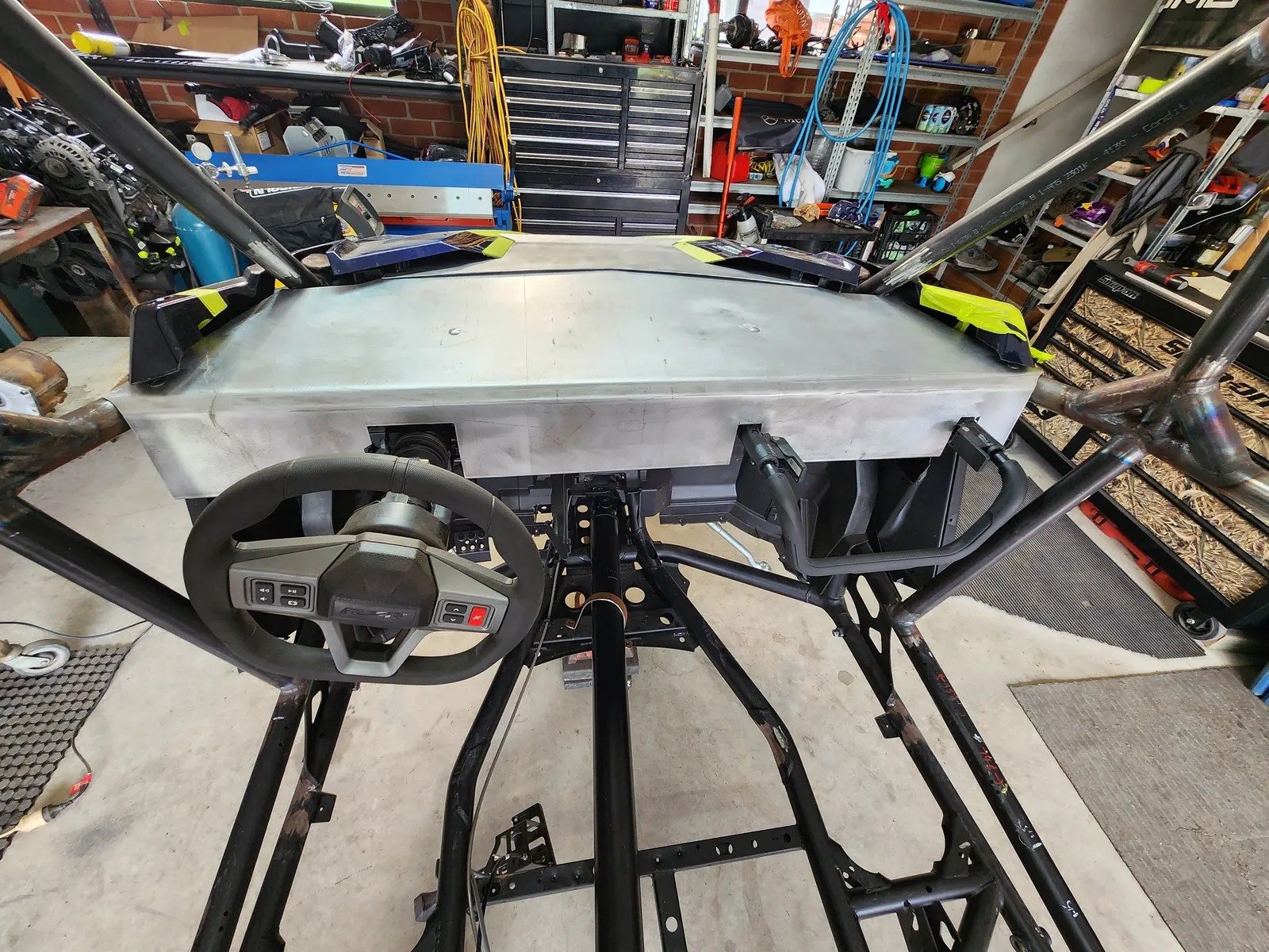 Raw aluminium dash panel fitted across the chassis, steering wheel mounted