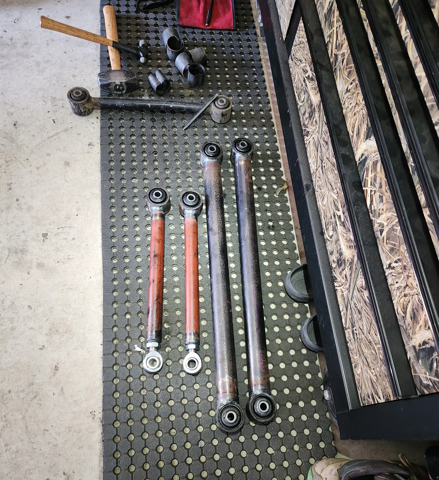 Four custom suspension arms with heim joints and bushes laid out on a rubber mat