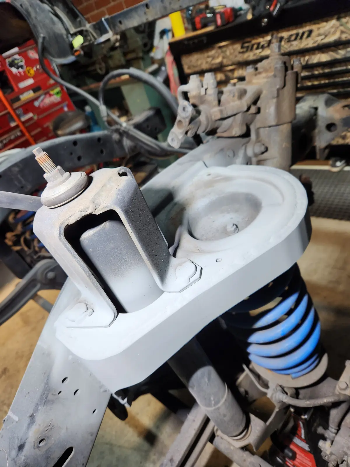 Painted spring tower with a welded support bracket above a blue coil spring