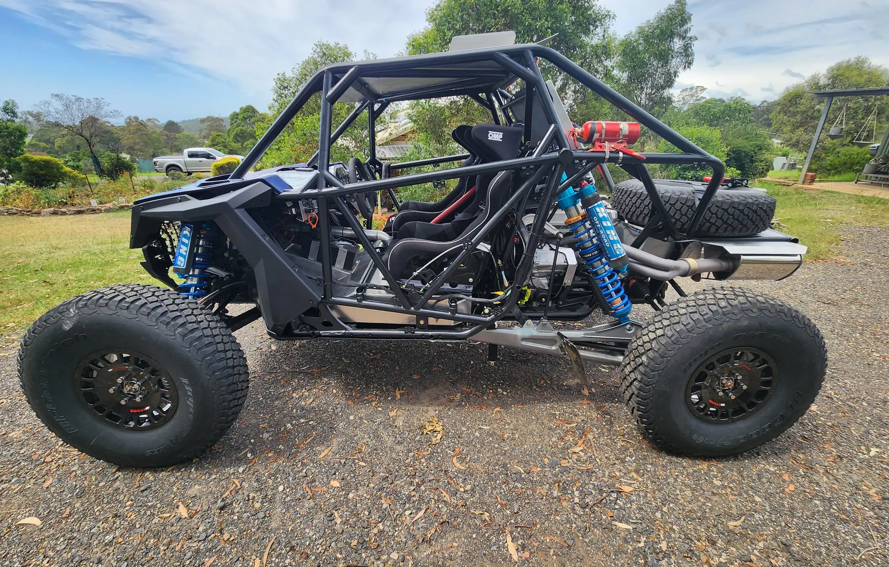 Side view of a custom tube-chassis race buggy with blue coil-over shocks