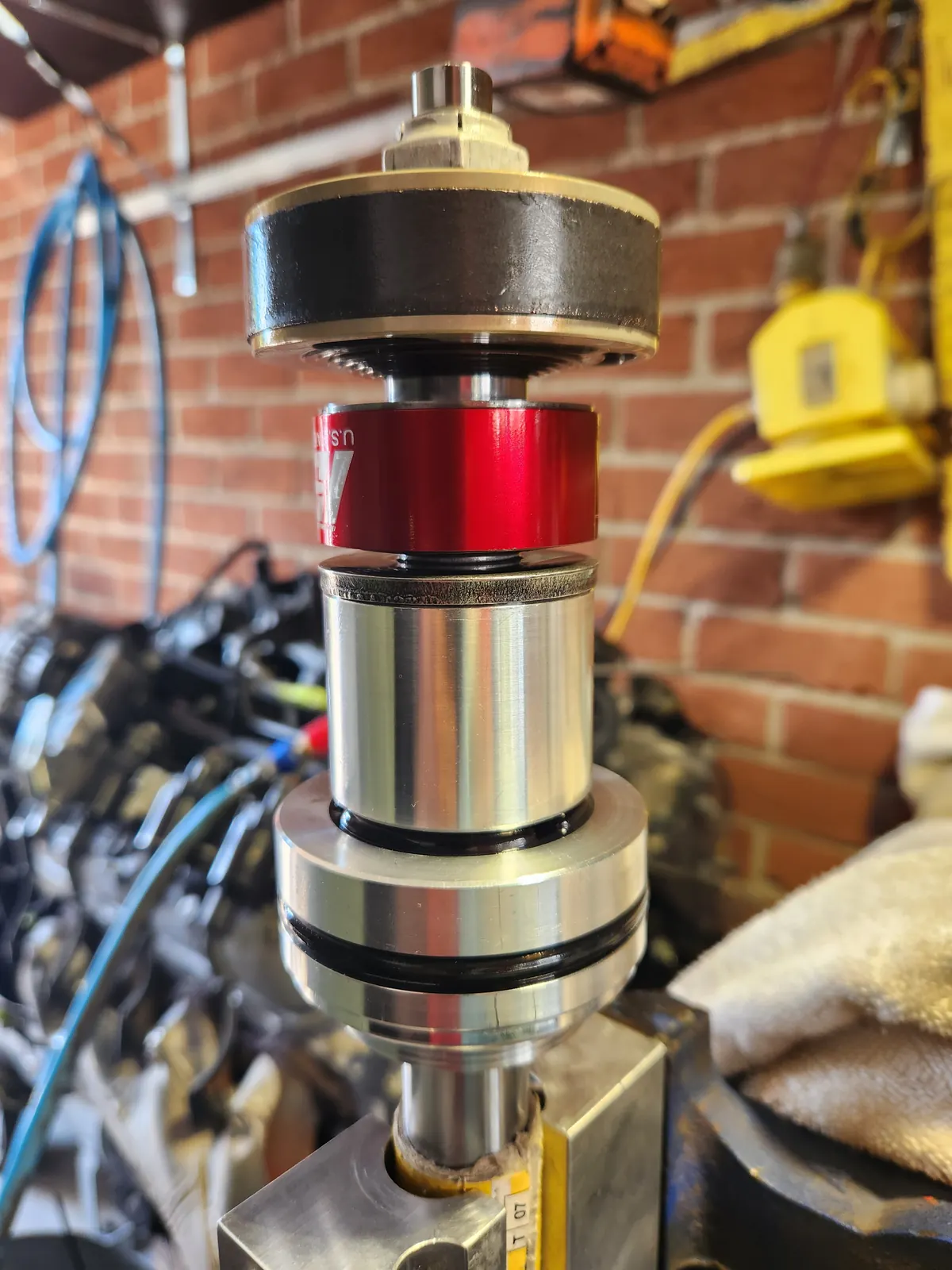Shock absorber shaft and piston held in a vice during a rebuild
